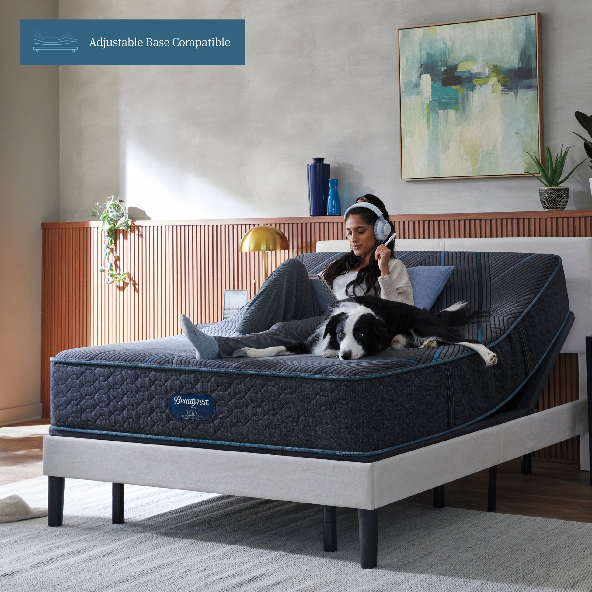 Woman sitting on Beautyrest Hybrid Medium-Firm Mattress with her dog writing on a notepad with her mattress elevated on an adjustable base.