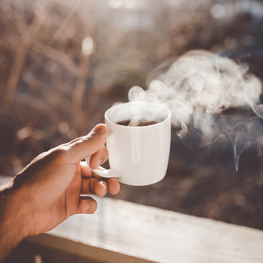 Hand holding cup of hot coffee.