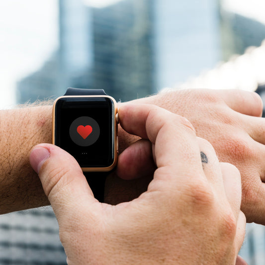 Closeup of a person pressing a fitness watch on their wrist with the screen showing a heart icon.