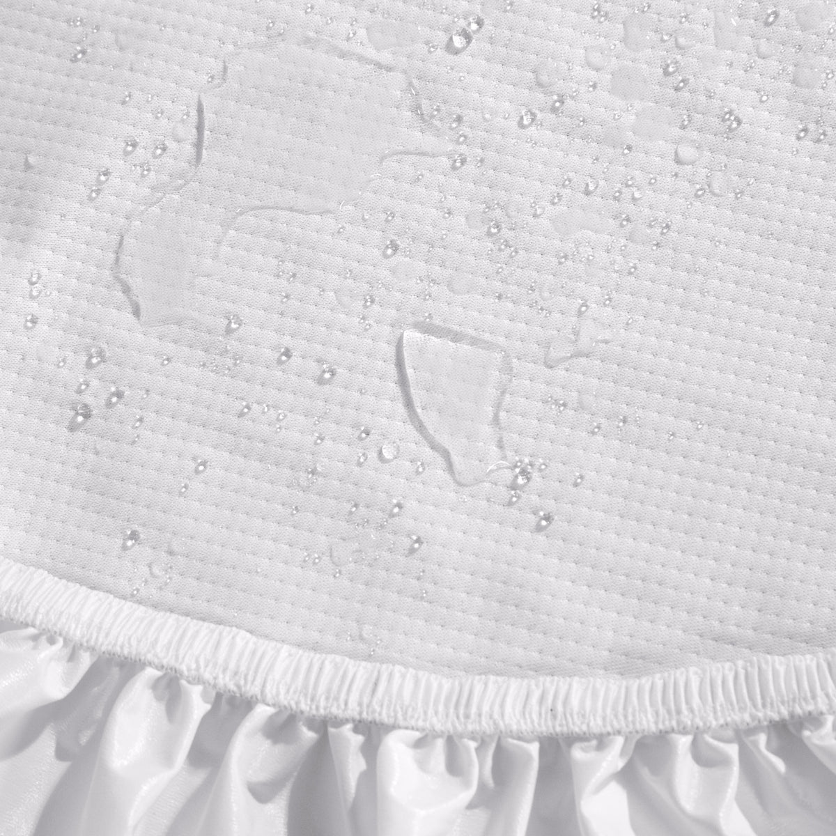 Close-up of a Beautyrest mattress protector with water droplets beading on top and a ruffled elastic hem at the bottom.