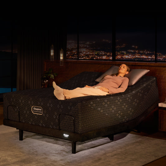 Woman laying on her back on top of a Beautyrest Black Hybrid mattress slightly elevated at the head of the bed on an Beautyrest Black Luxury adjustable base.