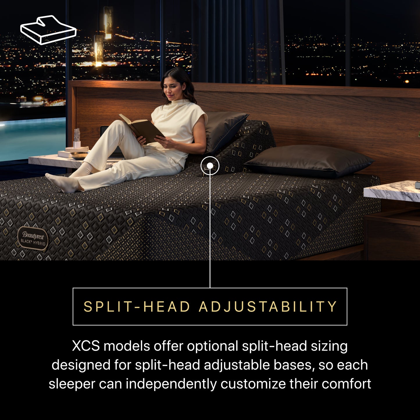 Woman reading a book on a Beautyrest Black Hybid XCS split-head adjustable bed with a cityscape view.