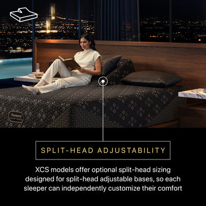 Woman reading a book on a Beautyrest Black Hybid XCS split-head adjustable bed with a cityscape view.