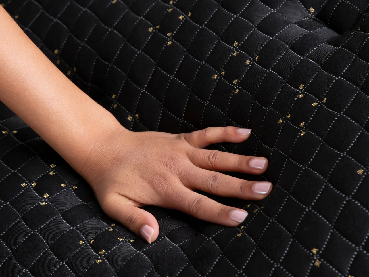 Close up of woman's hand pressing down on a quilted innerspring mattress