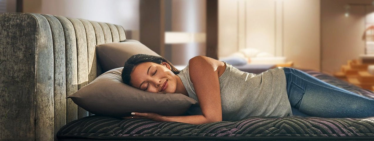 A woman smiling laying on a Beautyrest mattress in a showroom.